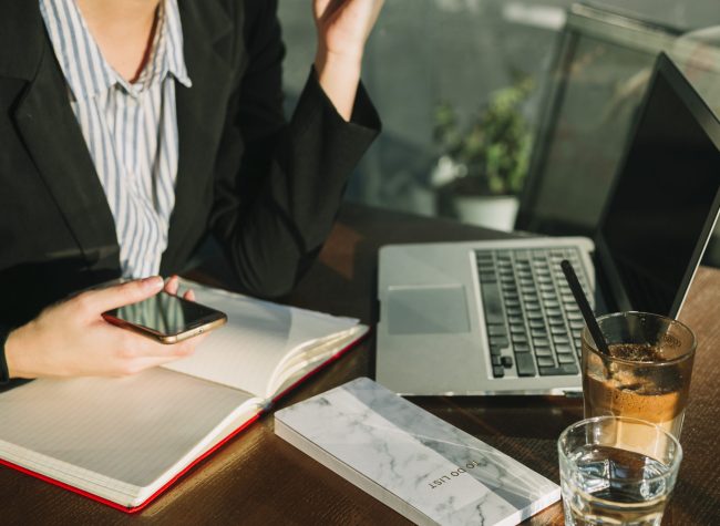 executiva-mao-segurando-cellphone-laptop-chocolate-milkshake-madeira-escrivaninha